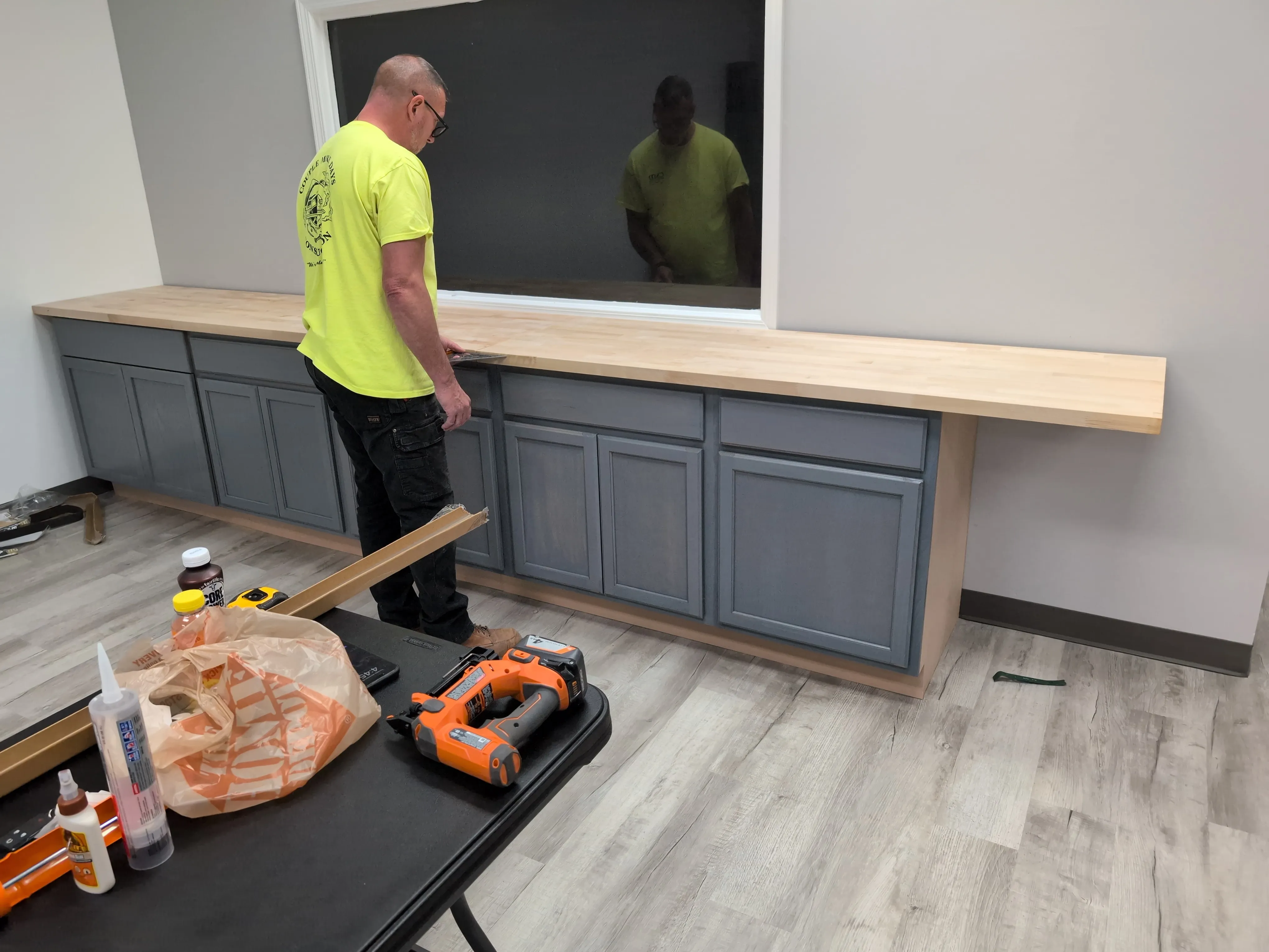 Joe McMorris building a long wall of gray cabinets with a butcher-block countertop inside the HUB.